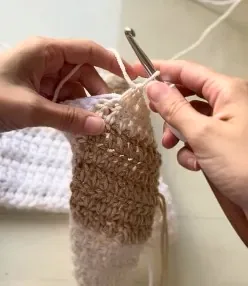 Hands crocheting a textured cream and tan piece
